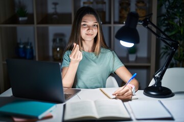 Teenager girl doing homework at home late at night doing money gesture with hands, asking for...