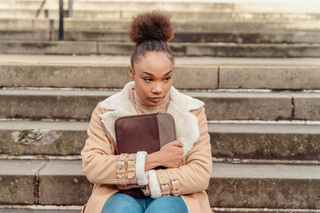 Obraz premium Upset woman student e-learning distance training course study working on stairs in the city. Multiethnic young woman watching online education webinar using a laptop