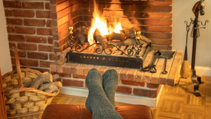 Feet with socks in front of the wood fireplace fire to warm them in winter.