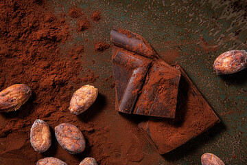 Tasy cocoa powder, beans and dark chocolate in a wooden background