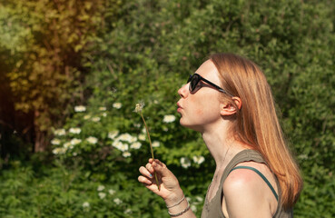 girl with red hair holding a dandelion in summer