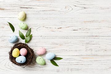 Colorful easter eggs in nest on table background with copy space top view