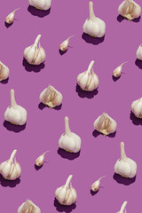 Pattern with fresh garlic on purple background.
