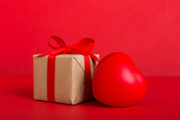 gift box with red bow and red heart on colored background. Perspective view. Flat lay