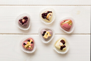 chocolate sweets in the form of a heart with fruits and nuts on a colored background. top view with space for text, holiday concept