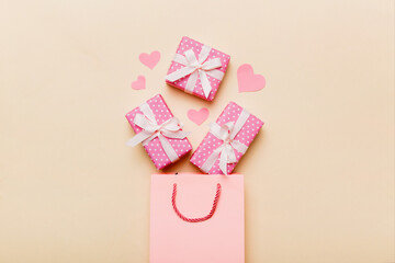 Gift boxes pop out from paper bag top view on colored background. bag packing handmade boxes fall out Concept of holidays, shopping, sale, discounts. Top view, flat lay