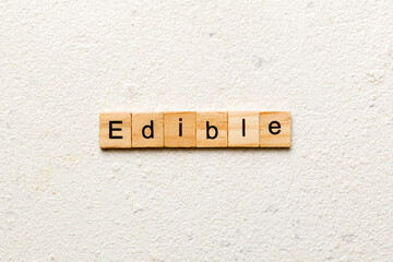EDIBLE word written on wood block. EDIBLE text on cement table for your desing, concept