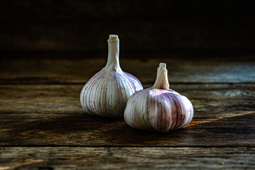 Two heads of garlic on a kitchen wooden table.