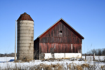 Weathered wooden barn in winter snow and blue sky