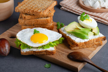 Sandwiches with curd cheese, fried egg, avocado and herbs