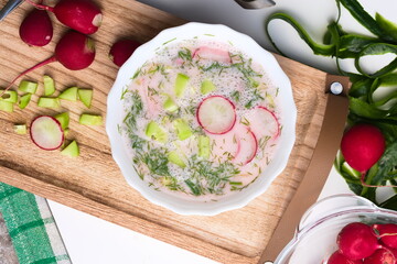 A bowl of soup with cream, served cold. Soup with radish, cucumber, dill and some spring onion. Chlodnik.