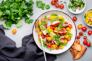 Grilled chicken salad with mango salsa, tomato, cilantro, red onion and lettuce in mexican style,...