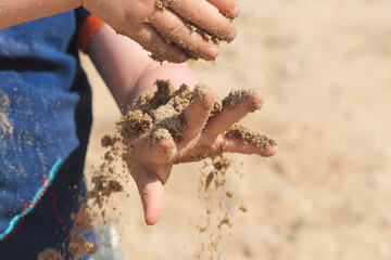 child's hands holding sand