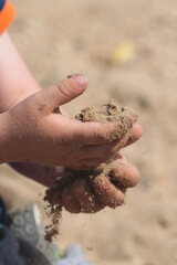 child's hands holding sand