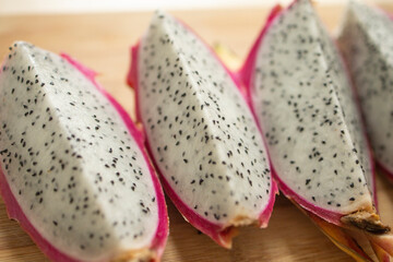 exotic dragon fruit of pink color, cut in half, on a wooden board. Weight loss, proper nutrition, diet, expensive fruits, slicing. Allergic to exotic.
