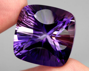 Natural gemstone purple amethyst on gray background