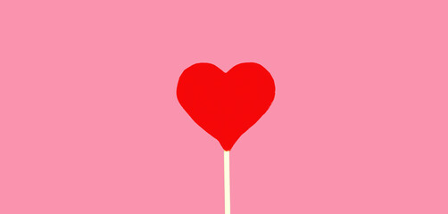 Close up sweet red heart shaped lollipop on pink background