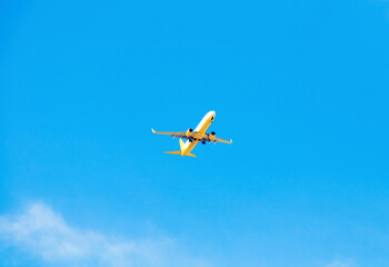 Fototapeta na wymiar Bottom view of flying plane in clear blue sky.