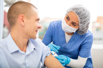 Obraz premium Female doctor ready to make injection to male visitor in hospital