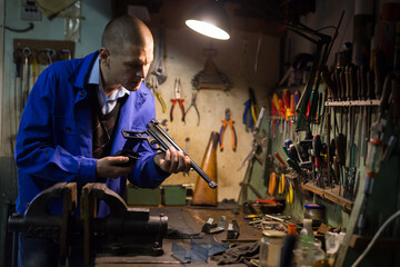 Fototapeta na wymiar Repair and lubrication of pistol in a weapons workshop