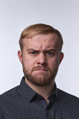Fototapeta premium Furious angry young business man, the emotion of resentment of a young man against a light background