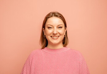 Portrait of cheerful pretty woman wearing pink sweater over pink background