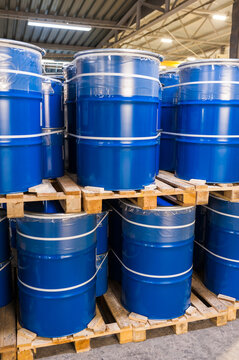 Blue metal barrels stacked in a Warehouse, vertical photo.