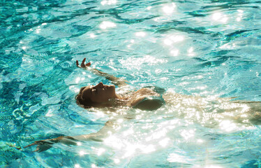 Beautiful happy brunette woman relaxing in a pool at summer