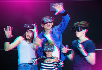 Modern cheerful family with two teen sons wearing virtual reality goggles playing video games...