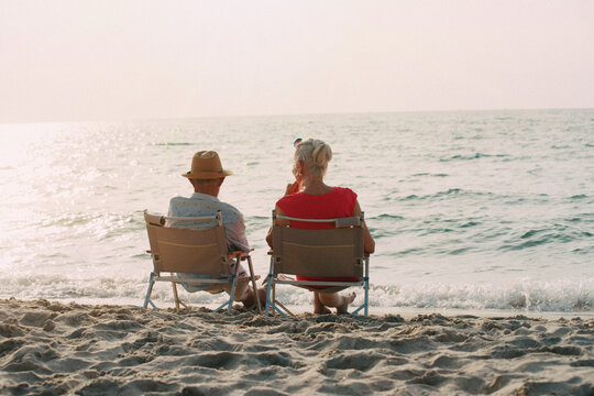 Happy Mature couple relaxing on beach at sunset, Retirement planning concept,Happy retired couple resting on beach chair on the beach and enjoying amazing view.
