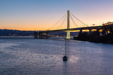 Early morning view of the Bay Bridge with a sailboat in the foreground