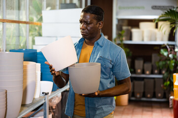 Portrait of african american man choosing pots for flowers and trees in gardening market