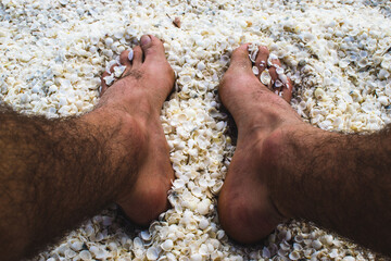 Male feet dept in shell beach