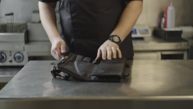 A professional chef chooses a knife from his set. The chef is preparing to prepare delicious dishes in the restaurant. Sharp and sharpened knives.