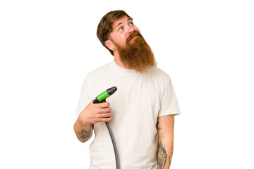 Adult man holding a watering hose isolated dreaming of achieving goals and purposes