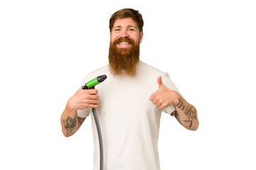 Adult man holding a watering hose isolated smiling and raising thumb up