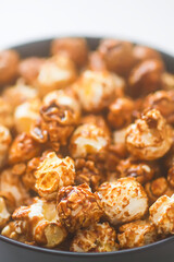 Sweet ready-to-eat popcorn in a black ceramic plate close up.