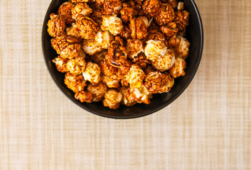 Sweet ready-to-eat popcorn in a black ceramic plate close up.