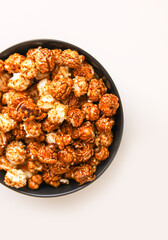 Sweet ready-to-eat popcorn in a black ceramic plate close up.