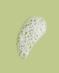 Foam swatch on green background. Soapy liquid texture with bubbles.