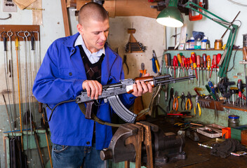 Gunsmith with Kalashnikov assault rifle in a weapons workshop