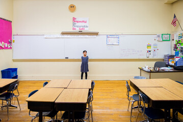 Young asian girl standing in elementary school classroom