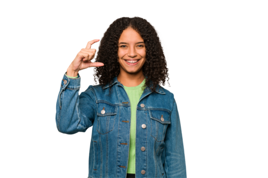 Young african american curly woman isolated holding something little with forefingers, smiling and confident.