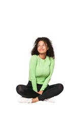 Young african american curly woman sitting on the floor isolated
