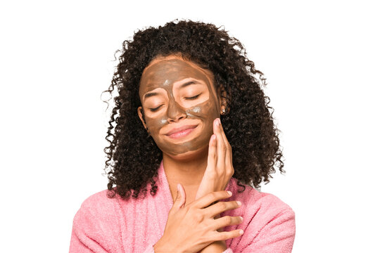 Young African American Curly Woman Wearing A Bathrobe And A Facial Mask Isolated