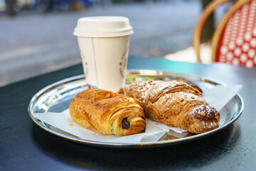 Delicious sweet breakfast served on metal plate consisted of fresh croissant, Pain au chocolat. Selective focus on Pain au chocolat and Almond Croissant crust 