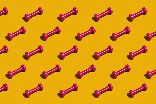 Bright pink dumbbells on a yellow background