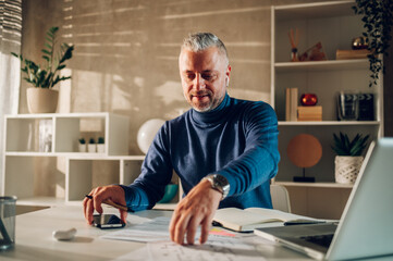 Middle aged man working in a home office with paper documents