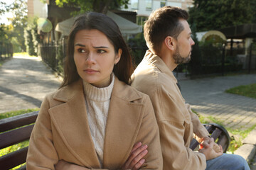 Upset arguing couple sitting on bench in park. Relationship problems