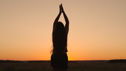 Young woman goes in for sports in park at sunset. Healthy girl is engaged in fitness, outside city in sun. Workout and warm-up in fresh air. Girl is engaged in gymnastics. Athlete exercising in nature